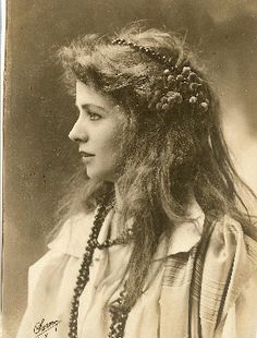 an old black and white photo of a woman with long hair wearing beads on her head