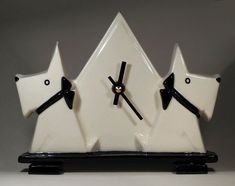 a clock with two white horses on it's sides and black hands, in front of a gray background