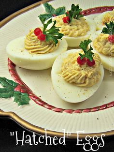 deviled eggs topped with whipped cream and garnished with holly leaves on a plate