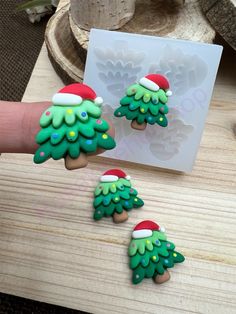 three decorated christmas trees sitting on top of a wooden table next to a paper card