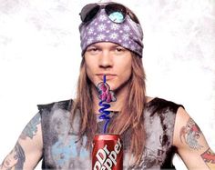 a man with long hair wearing a bandana and holding a can of soda in his mouth