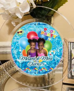 a glass plate with two children's faces on it and balloons in the background