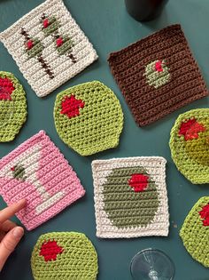 crocheted coasters are arranged on a table with a hand pointing at them