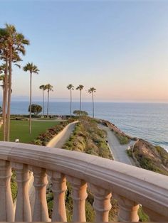 a balcony overlooking the ocean with palm trees on both sides and a path leading to the beach