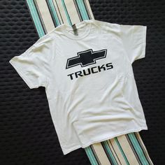 a white t - shirt with the words trucks on it sitting next to a pair of striped pants