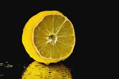 a half eaten lemon sitting on top of a reflective surface in front of a black background