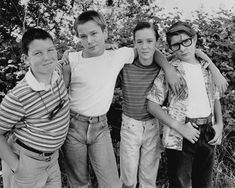 black and white photograph of four boys posing for the camera with their arms around each other