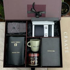 an open gift box containing two mugs, books and other items