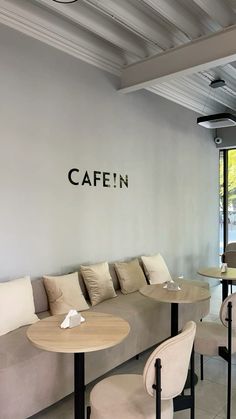 the interior of a cafe with tables, chairs and couches in front of a window