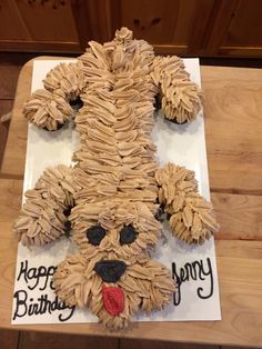 a dog made out of toilet paper sitting on top of a wooden floor next to a sign that says happy birthday