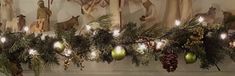 a christmas garland with ornaments and lights hanging from it's sides in front of a fireplace