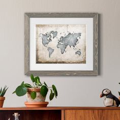 an old world map is hanging on the wall above a shelf with potted plants