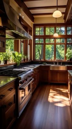 a kitchen with wood floors and large windows overlooking the trees in the distance is shown