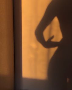 the shadow of a woman's torso and hand on her hip in front of a window