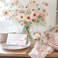 a table set with pink and white flowers in vases, plates, napkins and place cards