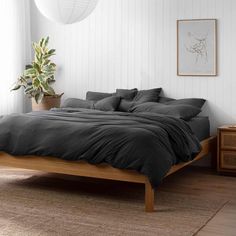 a bed sitting in a bedroom next to a wooden dresser and potted plant on top of it