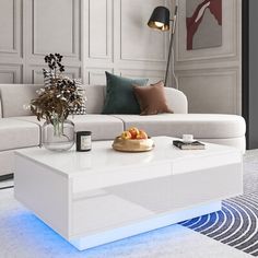 a modern living room with white furniture and blue lighting on the coffee table in front of it