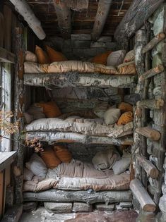 a room filled with lots of pillows and wooden shelves next to a wall covered in logs