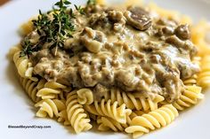 a white plate topped with pasta covered in mushroom gravy