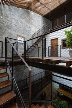 the inside of a building with wooden stairs and metal railings on each side, surrounded by greenery