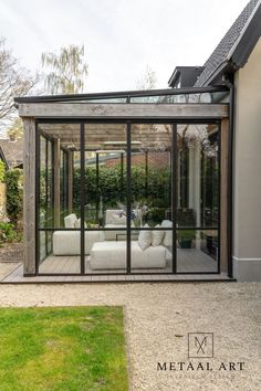 a living room with glass walls and sliding doors on the side of it, surrounded by grass