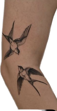 two small birds flying in the air on a woman's arm, one is black and white