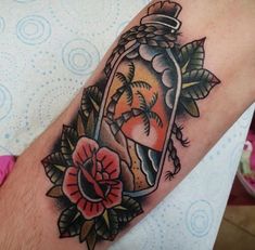 a man with a tattoo on his arm holding a jar filled with sand and flowers