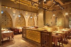 the interior of a restaurant with tables, chairs and lights hanging from the ceiling above