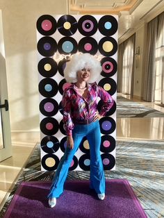 a woman standing on top of a purple rug in front of a giant display of records