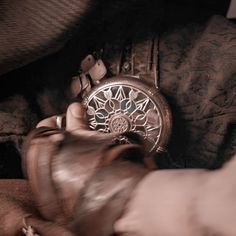 a person holding an antique pocket watch in their left hand and the other hand reaching for it