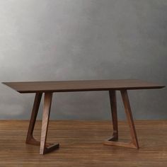 a wooden table sitting on top of a hard wood floor next to a gray wall