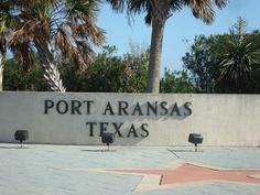 the entrance to port aranas texas with benches and palm trees in the foreground