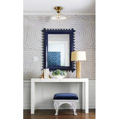 a white table with a blue chair and mirror on top of it next to a lamp