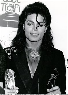 a black and white photo of michael jackson with his award for best rock album in front of him