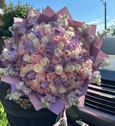 a bunch of flowers that are sitting in the back of a car, with purple and white colors