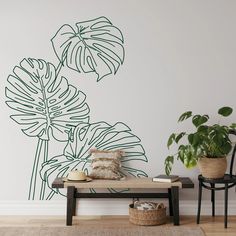 a living room with a bench, plant and wall decal