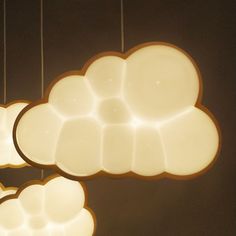 three lights hanging from the ceiling in a room with black walls and white clouds above them