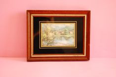 a painting hanging on a pink wall next to a wooden frame with an animal in it