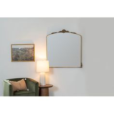 a green chair sitting next to a lamp on top of a hard wood floor under a mirror