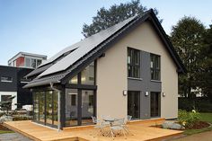 a house with a solar panel on the roof and patio area in front of it