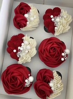 four cupcakes in a box decorated with red and white flowers, pearls and beads