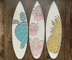 three surfboards with different designs on them sitting next to each other in front of a wooden wall