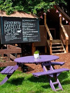 two purple picnic tables in front of a sign for leather bottle barbeque ranch