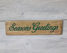 a wooden sign that says seasons greetings on the side of a white wood wall