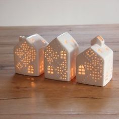 three small white house shaped lights on a wooden table