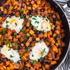 an iron skillet filled with eggs, black beans and sweet potato hashbrowns