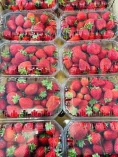 several plastic containers filled with strawberries on top of a table