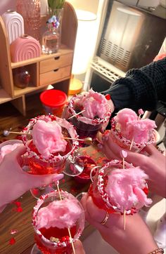 several people are holding up pink desserts on sticks