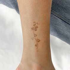 a woman's foot with a small tattoo on the side of her leg that has flowers growing out of it