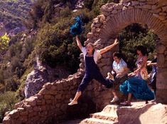 a woman jumping off some steps with her arms in the air and other people standing around